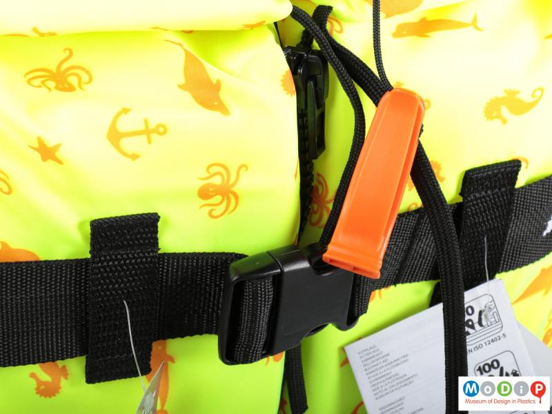Close view of a life jacket showing the whistle and buckle.