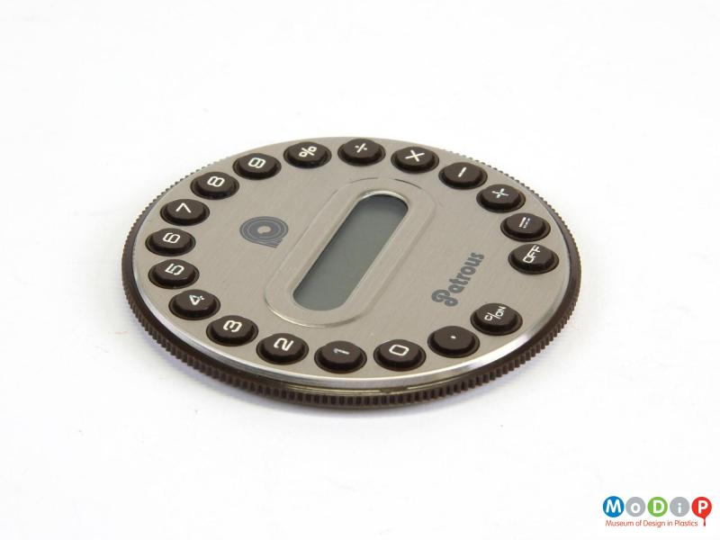 Side view of a Petrous PRMC-1 calculator showing the round buttons running around the edge, the display panel in the middle and the textured grip around the side.