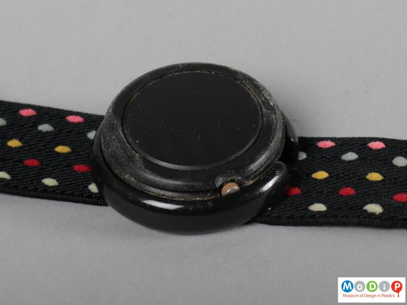Close view of a watch showing the back of the case which is popped out of the holder.