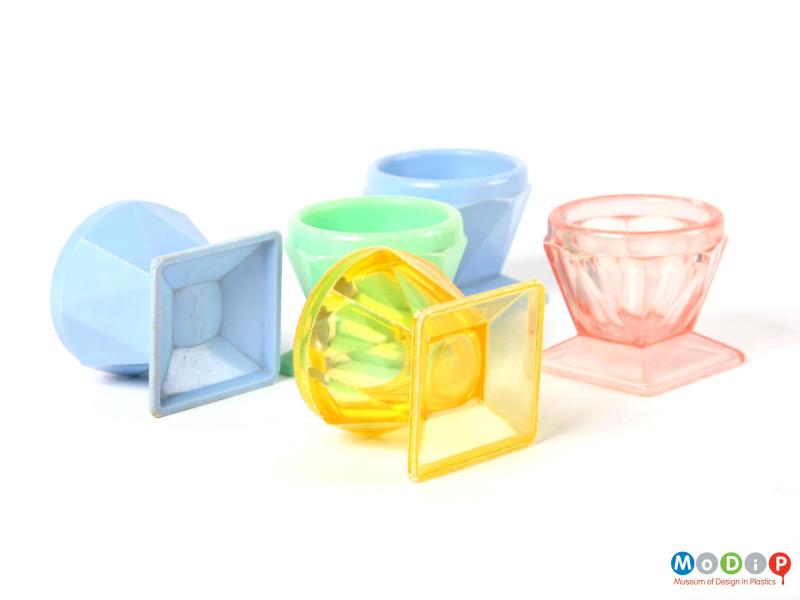 Side view of five Tudor Rose egg cups with a solid coloured and a crystal coloured egg cup on thier sides to show the underneath.