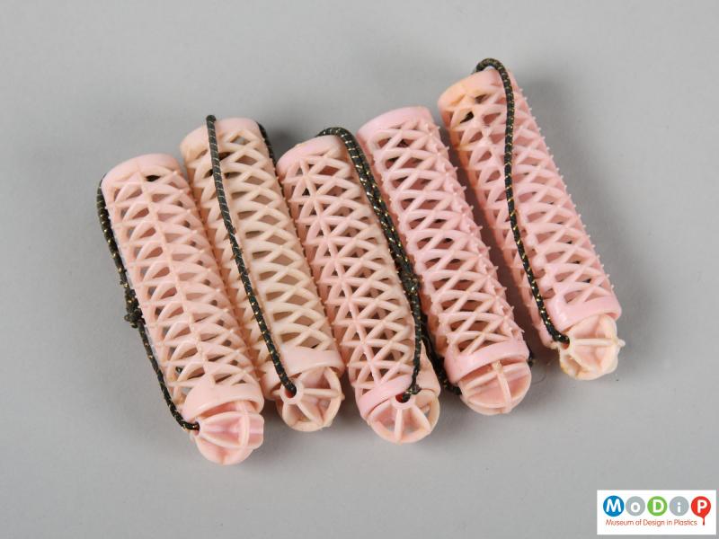 Side view of a set of curlers showing 5 pink curlers.
