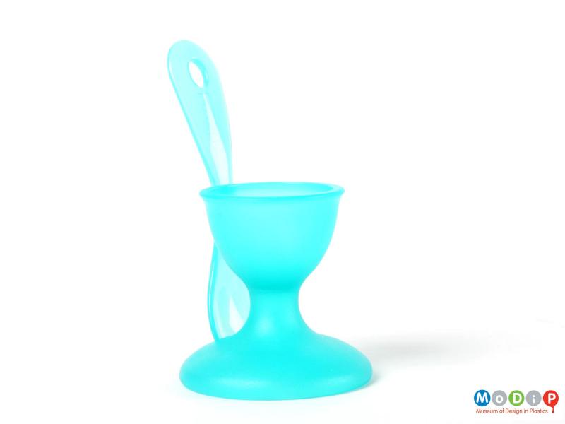 Side view of a Bodum egg cup with integral spoon showing the spoon at the side sitting in its slot in the foot of the egg cup.
