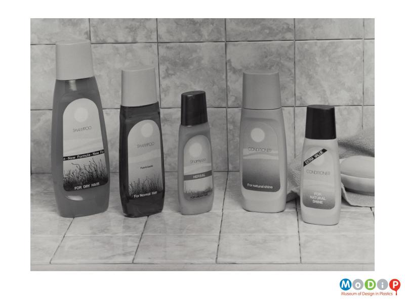 Scanned image showing 5 shmapoo and conditioner bottles in a bathroom setting.