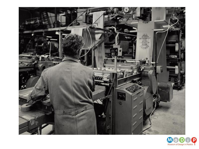 Scanned image showing a male worker operating an extruding machine.