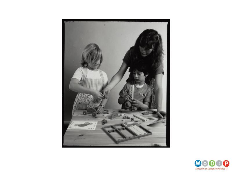 Scanned image showing two children and an adult woman playing with toys.