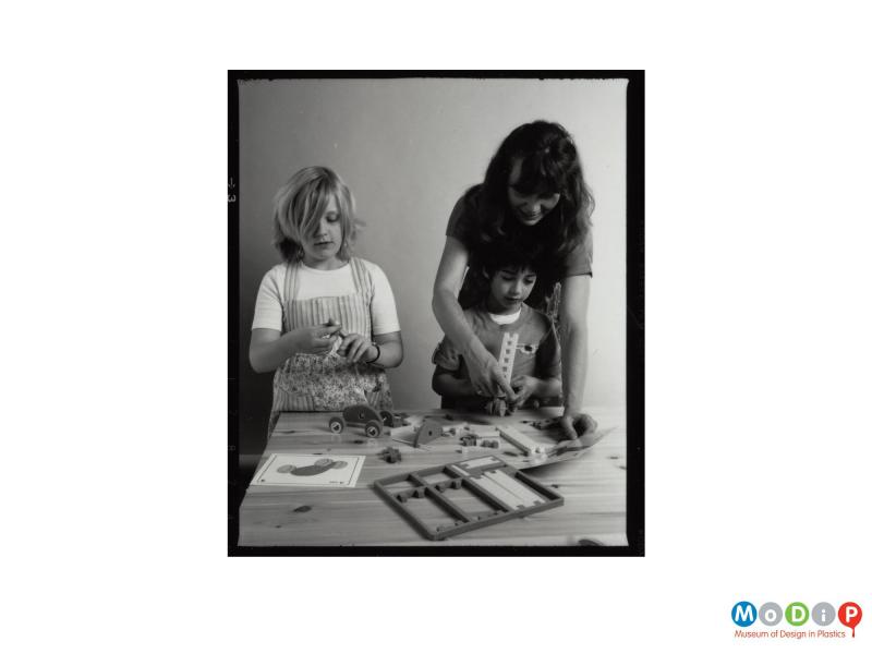 Scanned image showing two children and an adult woman playing with toys.