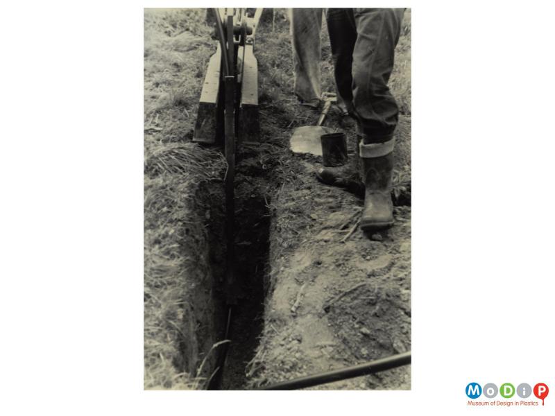 Scanned image showing a pipe being laid in a trench.