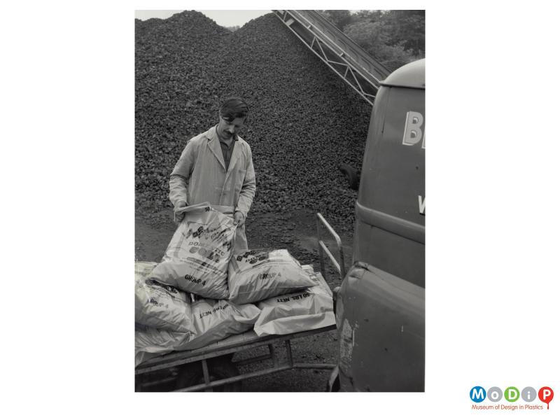 Scanned image showing sacks of coal being loaded into a van.