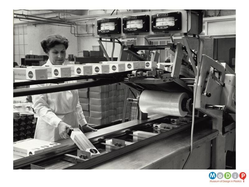 Scanned image showing boxes of nappies on a shrink wrap machine.