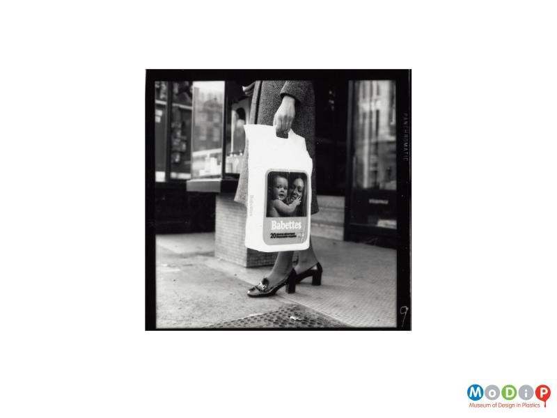 Scanned image showing a woman holding a bag of nappies.