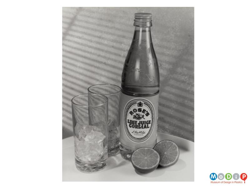 Scanned image showing a cordial bottle alongside 2 glasses and 2 lime halves.