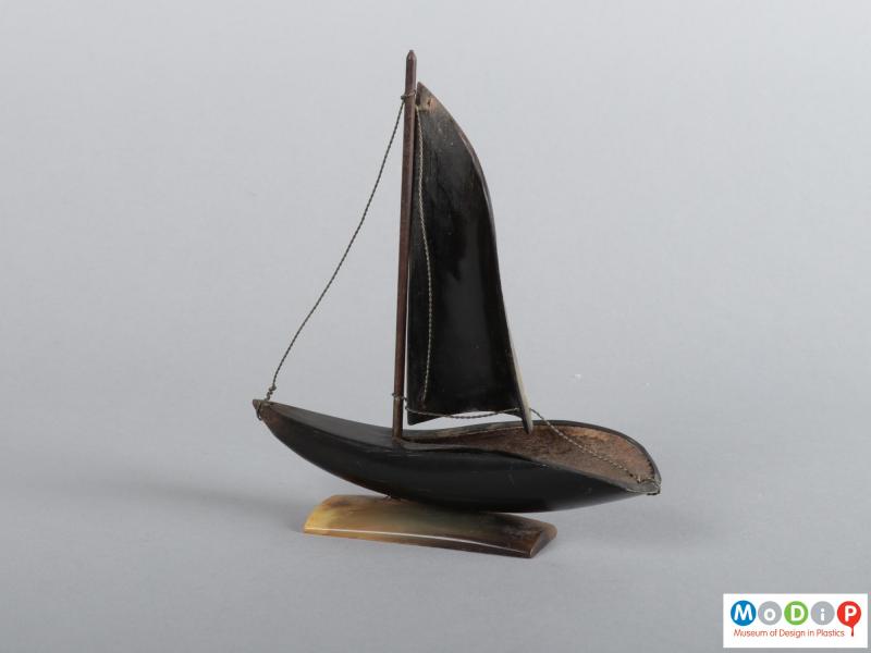 Side view of a horn boat ornament showing the hull and sail.