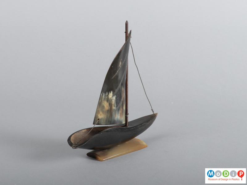 Side view of a horn boat ornament showing the hull and sail.