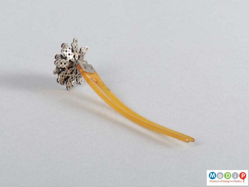Underside view of a hairpin showing the flower embellishment and two teeth.
