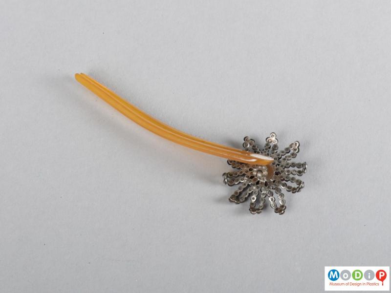 Underside view of a hairpin showing the floral embellishment and two teeth.