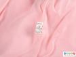Close view of a pink hooded coat showing the label on the inside seam.
