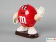 Side view of a red M&M figure showing the gloved hands.