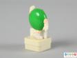 Side view of a green M&M figure showing the plain back.