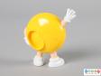 Rear view of a yellow M&M figure showing the back plate with a lipped hole on one side.