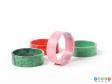 Side view of a set of four mottled napkin rings showing the pink and dark green rings at the front and the red and light green ring at the back.  The pink ring is on its side to show the inner and outer surfaces.