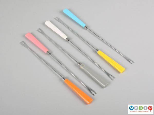 Top view of a set of fondue forks showing the coloured handles and two-pronged head.