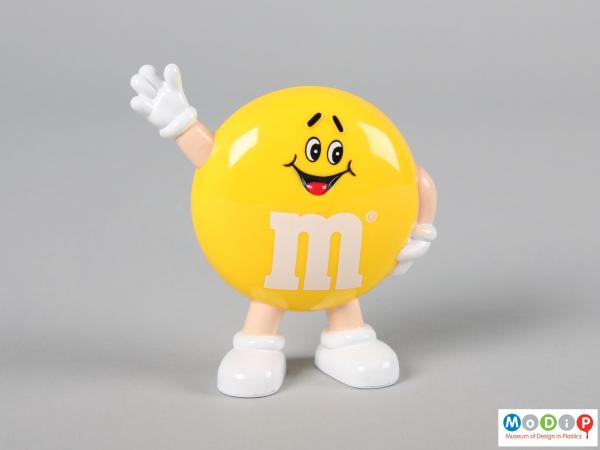 Front view of a yellow M&M figure showing the smiling face and the limbs.