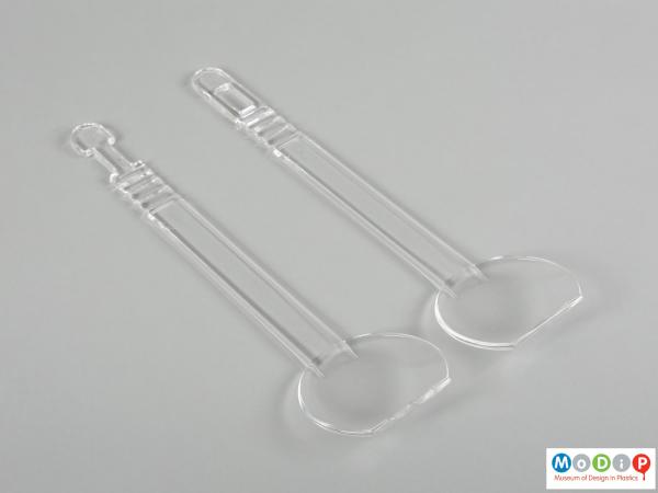 Top view of a pair of salad servers showing the long handles and round bowls.
