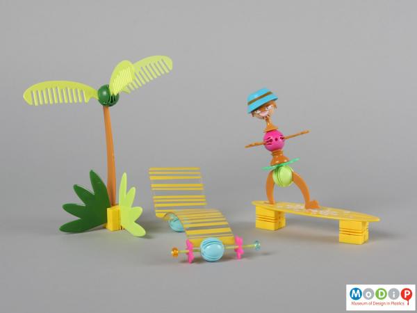 Front view of a construction set showing some of the pieces made into a palm tree, sun lounger, and person on a surfboard.