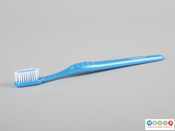 Side view of a toothbrush showing the ridged grip on the handle.