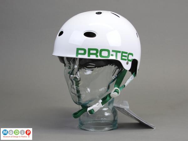 Side view of a bike helmet showing the smooth white surface and green chin strap.