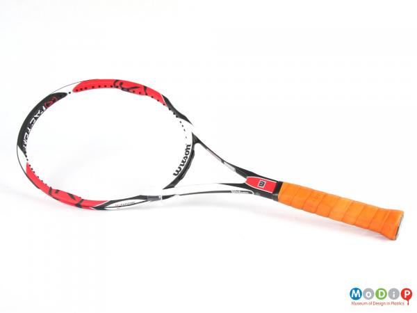 Side view of a tennis racket showing the oval shaped head and sraight handle.