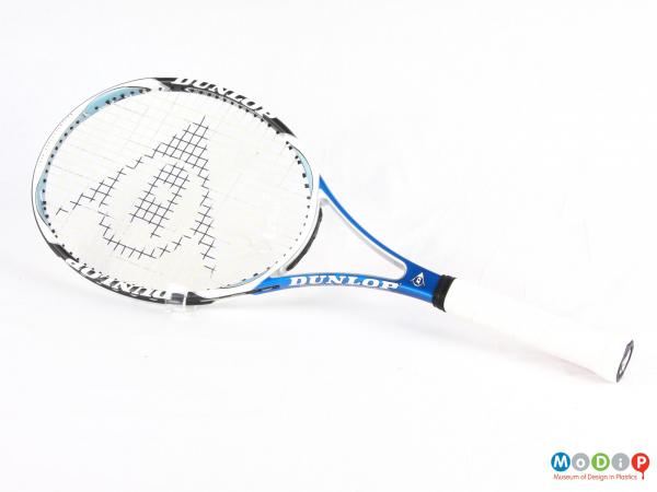 Side view of a tennis racket showing the oval head and straight handle.