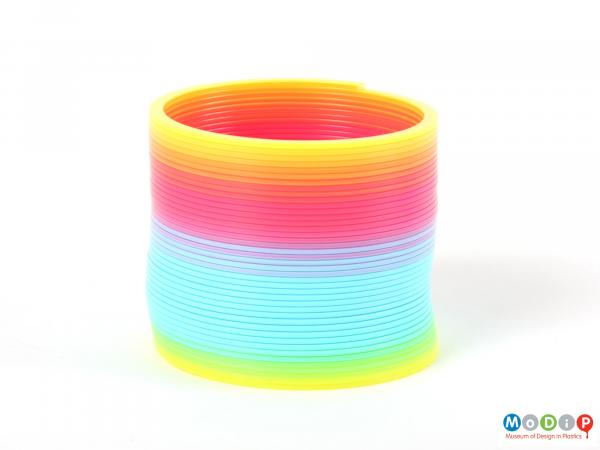 Side view of a plastic Slinky showing the full range of the colours.