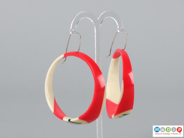 Side view of a pair of earrings made from pool balls hanging on an earring stand.