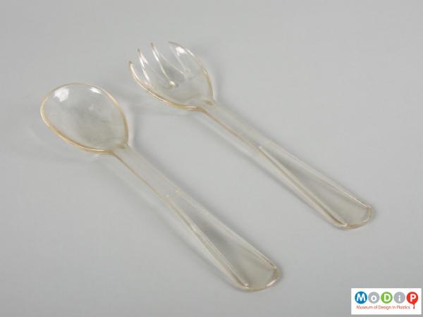 Top view of a pair of salad servers showing the straight handles and rounded bowls.