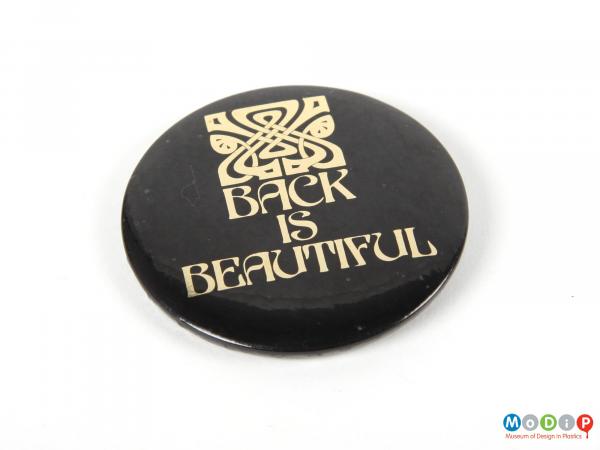 Front view of a Biba pin badge showing the printed inscription in gold on a black ground.
