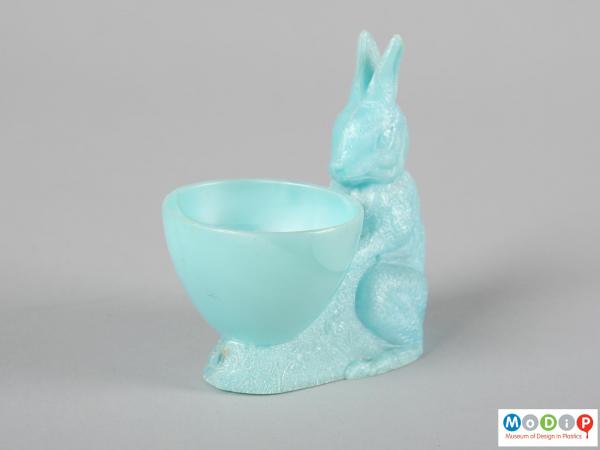 Side view of an egg cup showing the rabbit sitting behind the cup.