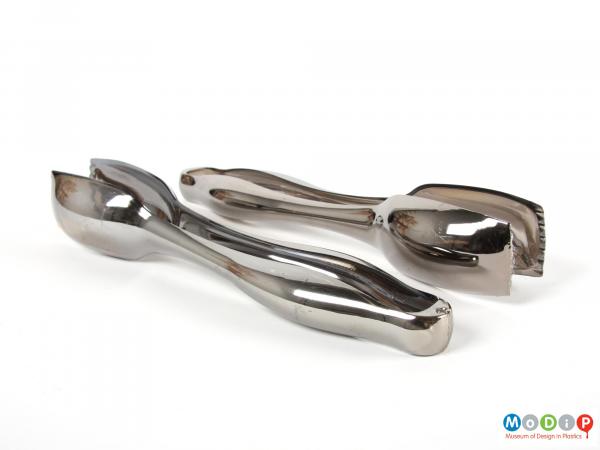 Side view of a 2 pairs of tongs showing the curved bodies.