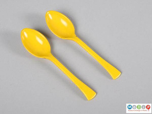 Top view of a pair of teaspoons showing the flaring handles and oval bowls,