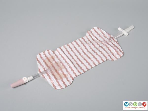 Side view of a urine bag showing the upper and lower tubing.
