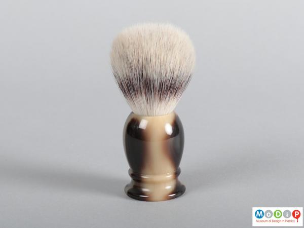 Side view of a shaving brush showing the handle and bristles.