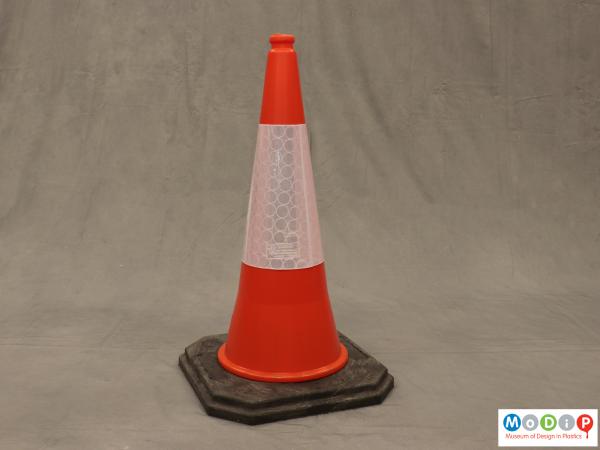 Side view of a traffic cone showing the black base and orange top section.