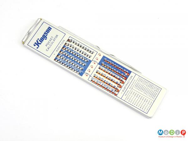 Top view of an Addiator mechanical calculator showing the sliding mechanism and the stylus in the holder.