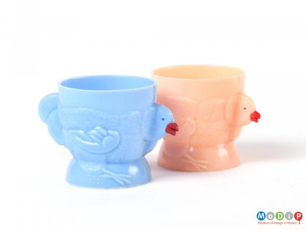 Side view of the blue egg cup standing in front of the pink egg cup.