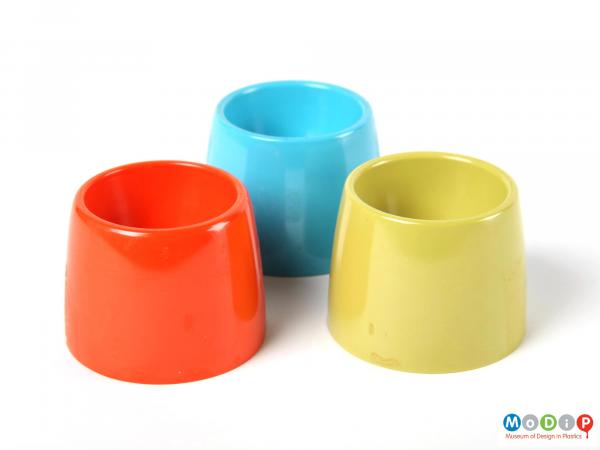 Side view of a plain green egg cup along side the red and blue egg cups which match it.