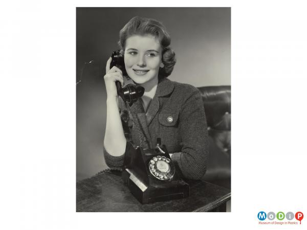Scanned image showing a woman using a telephone.