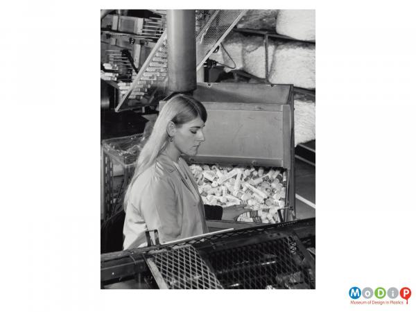 Scanned image showing a female worker sorting containers.