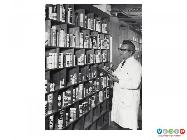 Scanned image showing a man inspecting a display of tubes.