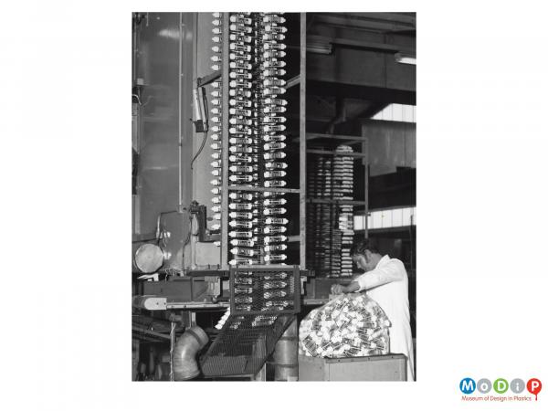 Scanned image showing a male worker alongside a tube producing machine.