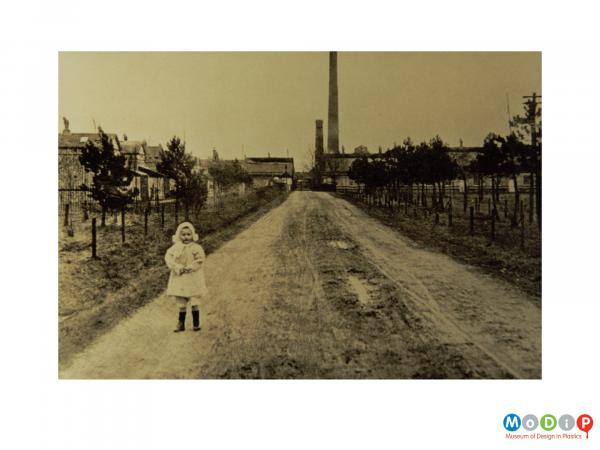 Scanned image showing a small child standing near a factory.